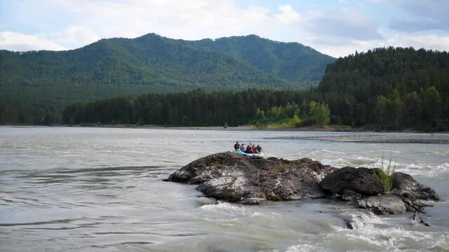 Group of people sails in the inflatable boat on the mountain river. Rafting sports