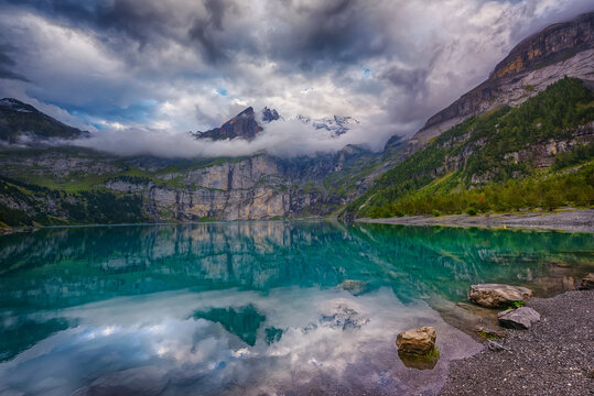 Soft evening light over the Swiss alps and lake on a cloudy day at Oschinensee Switzerland. It's a beautiful UNESCO heritage site with amazing landscapes and hiking trails. 

