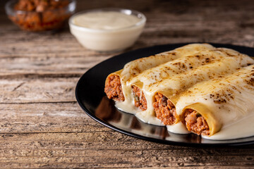 Delicious meat cannelloni pasta on wooden table. Copy space	