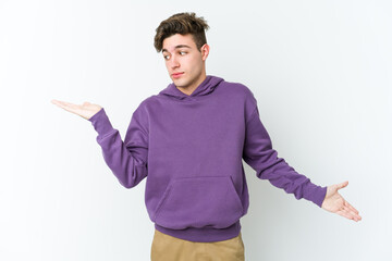 Young caucasian man isolated on white background confused and doubtful shrugging shoulders to hold a copy space.