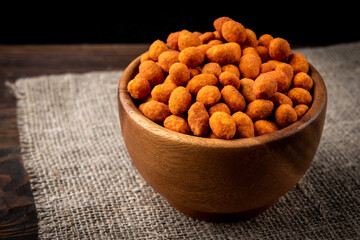 Paprika roasted peanuts on dark wooden background. Delicious snack peanut.