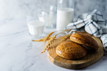 Rye bun in a plate with glasses of milk