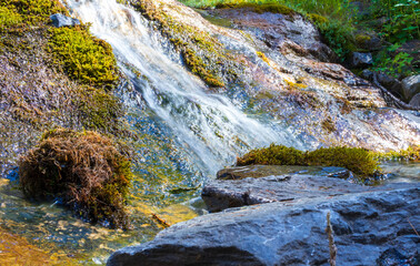 river in long exposure with natural elements, moss, plants and rocks close up 