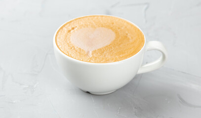 White cup of hot cappuccino coffee on concrete background