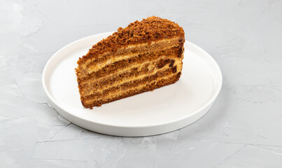 Homemade honey cake on a white dish on a concrete background