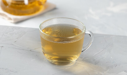 Green tea in a glass transparent cup with hot water on a concrete background