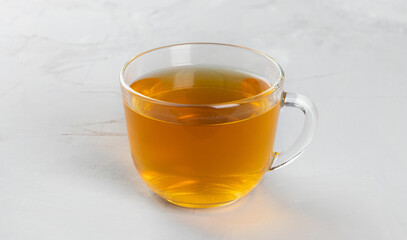 Yellow tea in a glass transparent cup with hot water on a concrete background