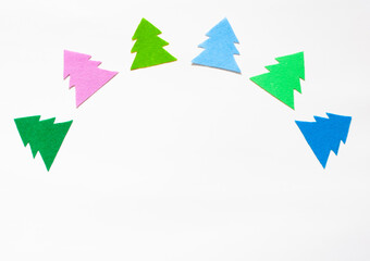 Multi-colored silhouettes of Christmas trees laid out in a semicircle on a white background, copy space
