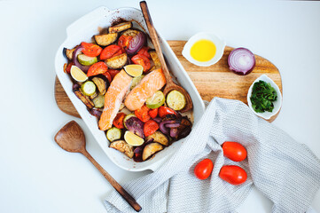 cooking healthy diet vegetarian food - mixed oven roasted vegetables with baked salmon filet. Eggplant, zucchini, tomatoes and red pepper with herbs.