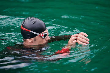 triathlon athlete swimming on lake setting smartwatch