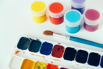 Colorful gouache paints and brush for painting on white background. Copy, empty space for text