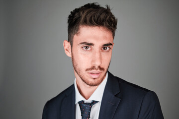 Young man close up portrait wearing a dark blue suit and a dark blue tie with red and light blue dots.