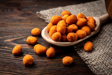 Paprika roasted peanuts on dark wooden background. Delicious snack peanut.