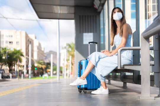 Virus protection in public transportation. Woman traveling wearing protective mask. Virus pandemic and pollution concept. Woman waiting at train station. High quality photo