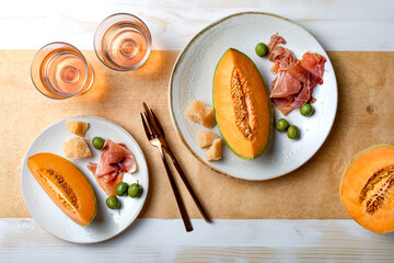 Fresh cantaloupe melon with ham, cheese and green olives with glass of rose wine. Traditional Spanish and Italian appetizer, antipasti snack. Top view