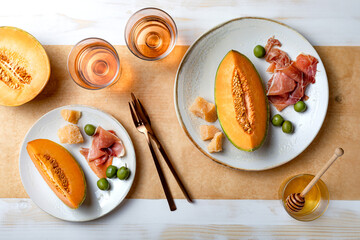 Fresh cantaloupe melon with ham, cheese and green olives with glass of rose wine. Traditional Spanish and Italian appetizer, antipasti snack. Top view