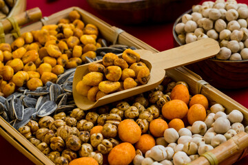 Roasted and salted mixed nuts are designed on a wicker tray with wooden shovel