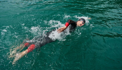 triathlon athlete swimming on lake wearing wetsuit