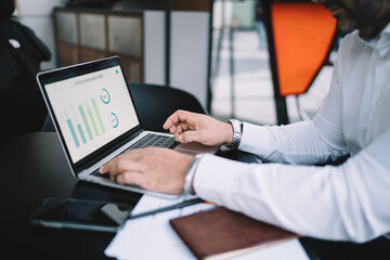 Cropped image of male professional working remotely with web statistics analyzing informative graph chart, skilled financial expert checking digital marketing report during distance job via netbook