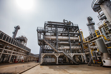 Oil refinery and gas processing plant. Grey metal distillation tower (refinery column), tanks and...