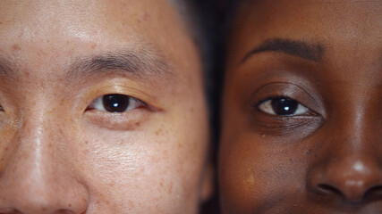 Macro portrait of attractive positive afro-american female and asian male faces next to each other