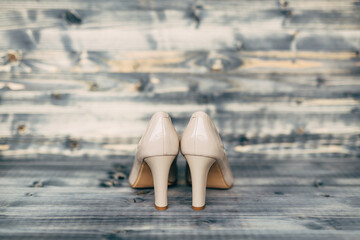 Beige high-heeled bridesmaid shoes on gray wooden texture.