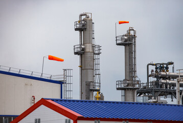 Distillation towers with orange weather vanes on grey sky background. Oil refinery and gas...