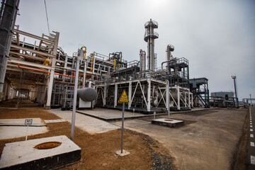 Oil refinery and gas processing plant in desert on the yellow sand. Distillin towers and pipelines. Sulphur (sulfur) dioxide yellow warning sign.