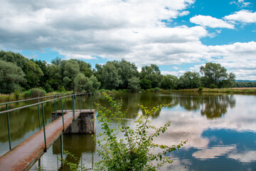 Banska Bystrica, Slovakia. Trees mirror reflection in the water. Fishing place. Shining sun over the fish pond in summer day.