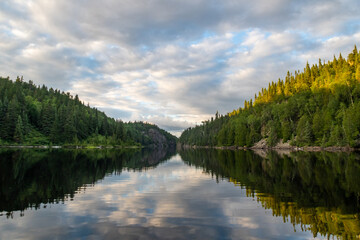 Fototapeta na wymiar View of a peaceful lake with trees reflecting in the water in the Aiguebelle national park, Canada