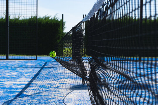 Paddle tennis ball smashed on the net in an outdoor paddle tennis court.