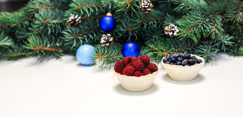 Obraz na płótnie Canvas Christmas layout. Berries on the table, blue decorations on the fir branches. New Year
