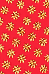 Christmas gold ribbon bow pattern on red background. Design composition for wrapping paper, birthday, christmas or greetings card. 