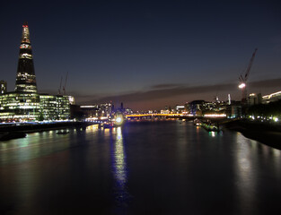 City skyline after sunset with the Shard, Southwark Bridge and Tower Bridge across Thames river with night lights in London, United Kingdom