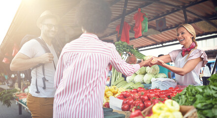 Seller woman offers fresh and organic vegetables at the green market or farmers market stall.  Young buyers choose and buy products for healthy food in grocery. All for diet healthy eating, lifestyle.