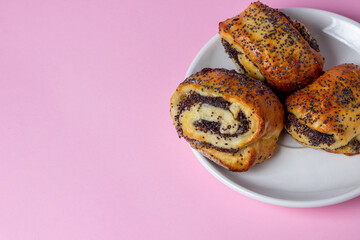 Rolls with poppy seeds on a pink background. Homemade baking. Sweet pastries