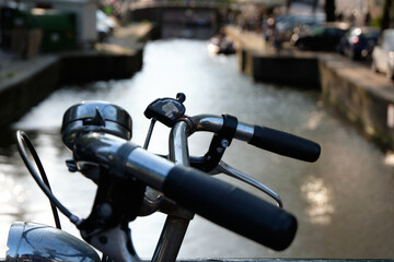 Handlebars of a bicycle parked alongside a canal in Amsterdam