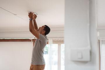 African American Man changing light bulb during COVID-19 quarantine at home