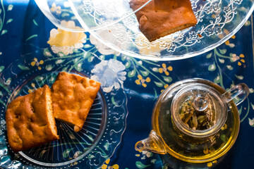 Cup of fresh flower and herb arabic tea and some Tasty and healthy almond cookies, rich in vitamins and less sugar. copy space.Top view on a blue flowers background..