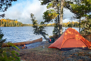 Campsite with orange tent on northern Minnesota lake during autumn