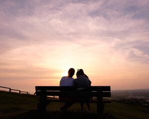 Fototapeta na wymiar silhouette of couple sitting on bench at sunset