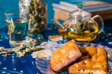 Fototapeta na wymiar Cup of fresh flower and herb arabic tea and some Tasty and healthy almond cookies, rich in vitamins and less sugar. copy space.Top view on a blue flowers background..
