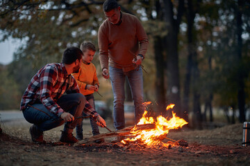 Happy  Grandfather, father and son at camping with campfire at night ;  Quality family time concept