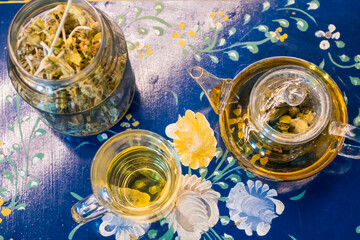 Cup of fresh flower and herb arabic tea and some Tasty and healthy almond cookies, rich in vitamins and less sugar. copy space.Top view on a blue flowers background..