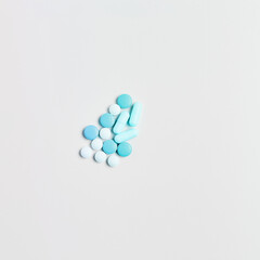 minimal medicine concept. pills and capsules of blue color on a white background. top view, square frame
