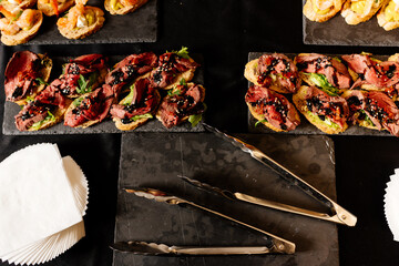 Bruschetta on black table with napkins and kitchen tongs
