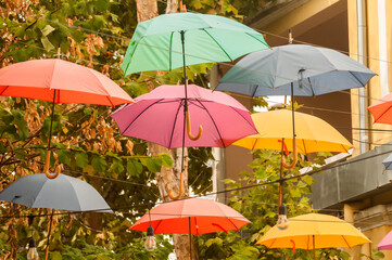 Fototapeta na wymiar Umbrellas in different colors hanging over city street