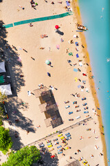 City beach with clean azure water and a lot of tourists lying on the warm sand - top view shot with a drone