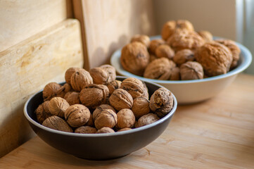 Walnuts on table in hard shells, group of dry ripened fruits in bowl, crop food ingredients ready for cooking