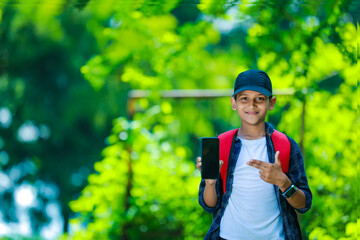 childhood, technology and people concept - indian cute school boy showing smartphone with blank screen